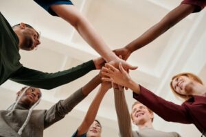 pexels-photo-6146697-6146697 A diverse group of young adults forming a united circle with hands together indoors.